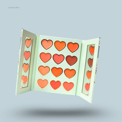 Open Plouise blush palette featuring heart-shaped pans in shades of orange, pink, and red.
