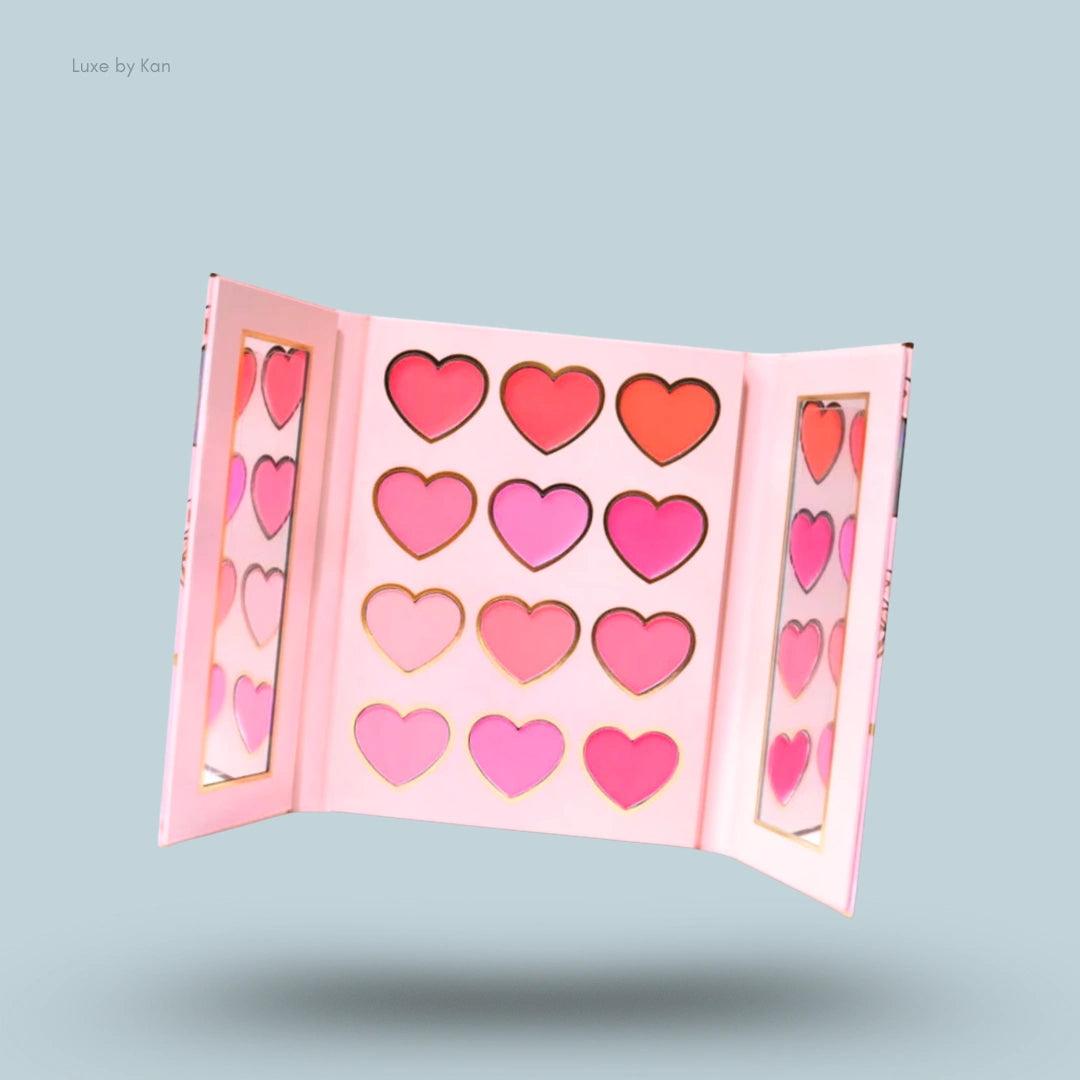 Open Plouise blush palette with twelve heart-shaped pans of varying pink and red blush shades, with side panels containing mirrors.