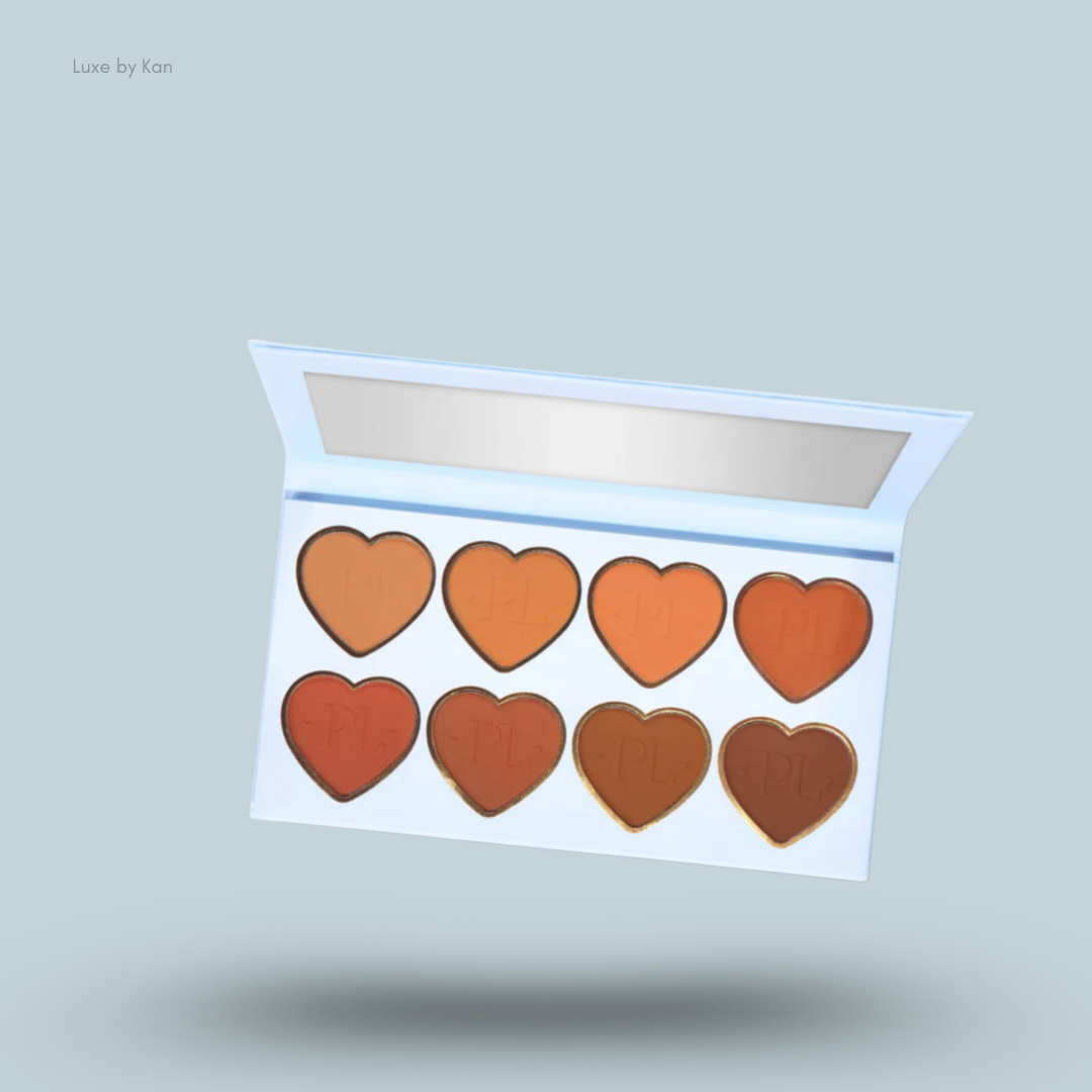 Open Plouise bronzer palette with eight heart-shaped compartments containing bronzer in varying shades of orange and brown.