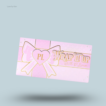 Pink and gold Plouise "Wrap It Up" highlighter palette with a bow design and heart-shaped logo.