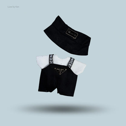 Labubu doll baddie streetwear outfit: black visor, white shirt, and black overall shorts with "NICE" straps and Prada logo.