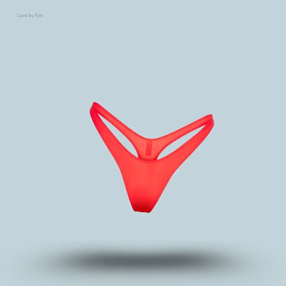 SKIMS Shine Foundations Dipped Thong in Poppy, flat lay on light blue background