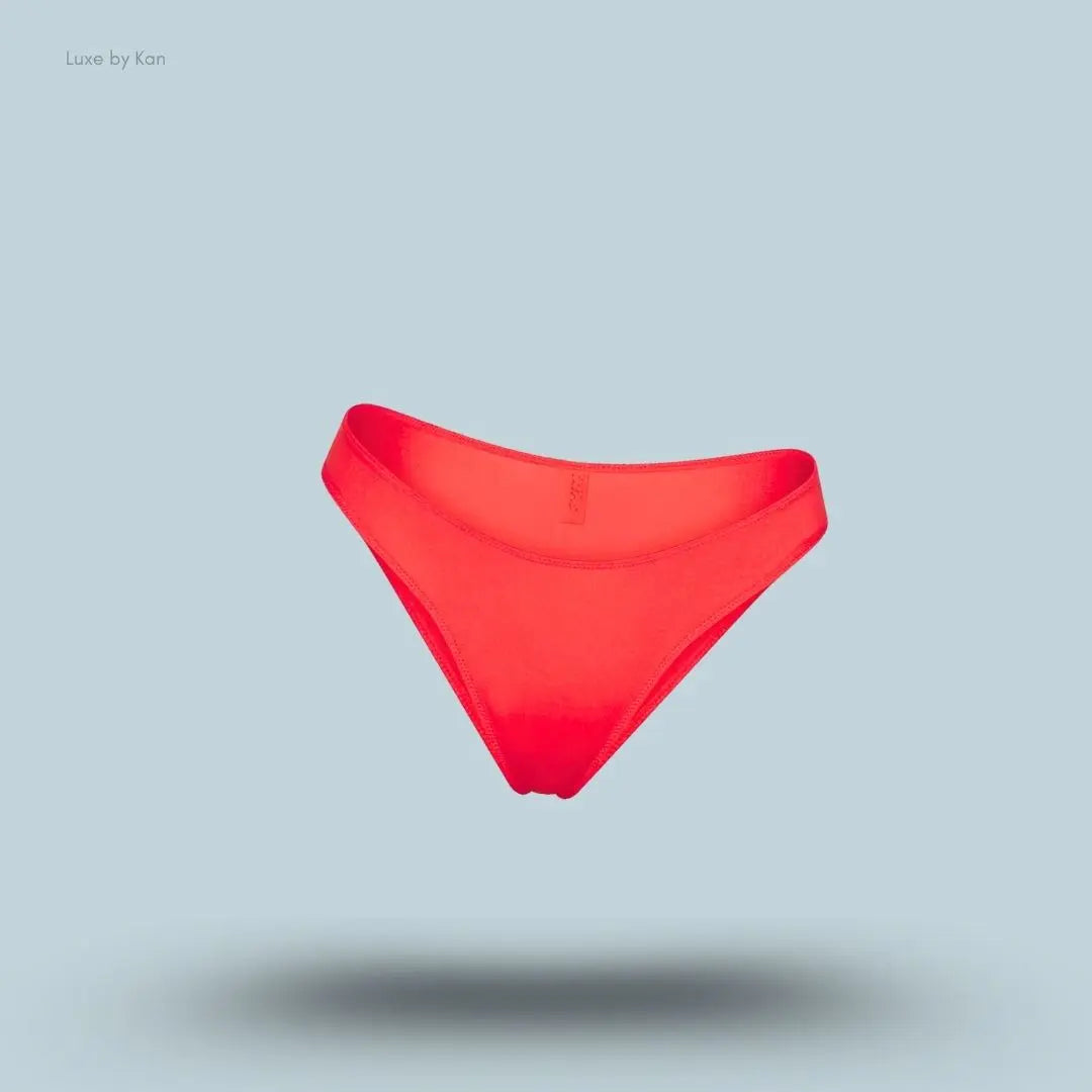 SKIMS Shine Foundations Dipped Bikini in Poppy, flat lay on light blue background