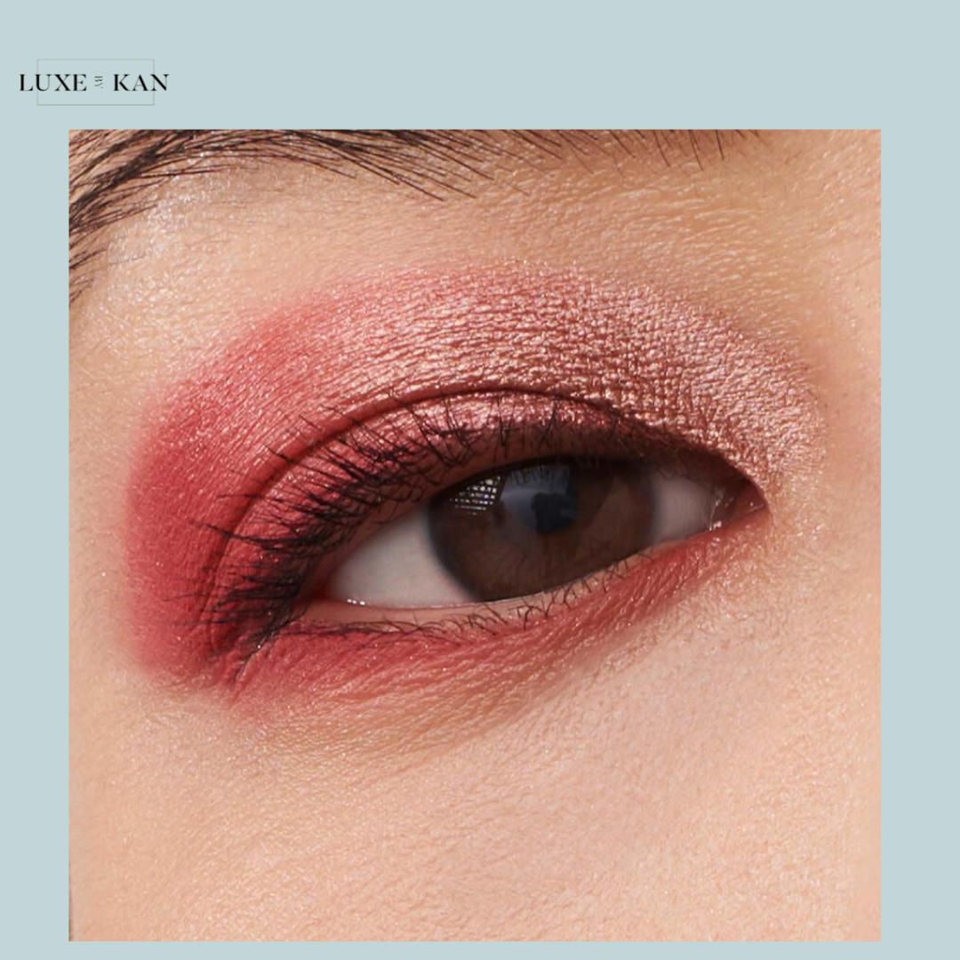 Close-up of a brown eye with shimmering rose and pink eyeshadow, accentuating the eyelid and lower lash line.