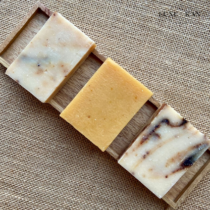 Three anar & pink salt luxury cold soap on a wooden tray, featuring swirls of cream, brown, and a solid golden hue.