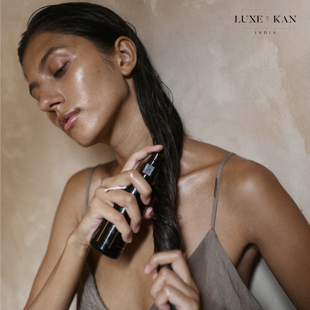 A person is applying Kesha Fortifying Hair Oil to their hair.