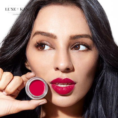 A person with long, dark hair holding up a Laali Lip Paint Pot.