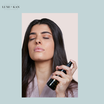 A person holds a sambac botanical essence bottle, showcasing long, shiny hair while wearing a light-colored robe.