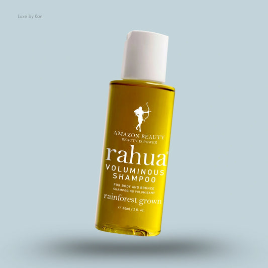 A bottle of Rahua voluminous shampoo, with its golden liquid contents visible through the clear plastic.