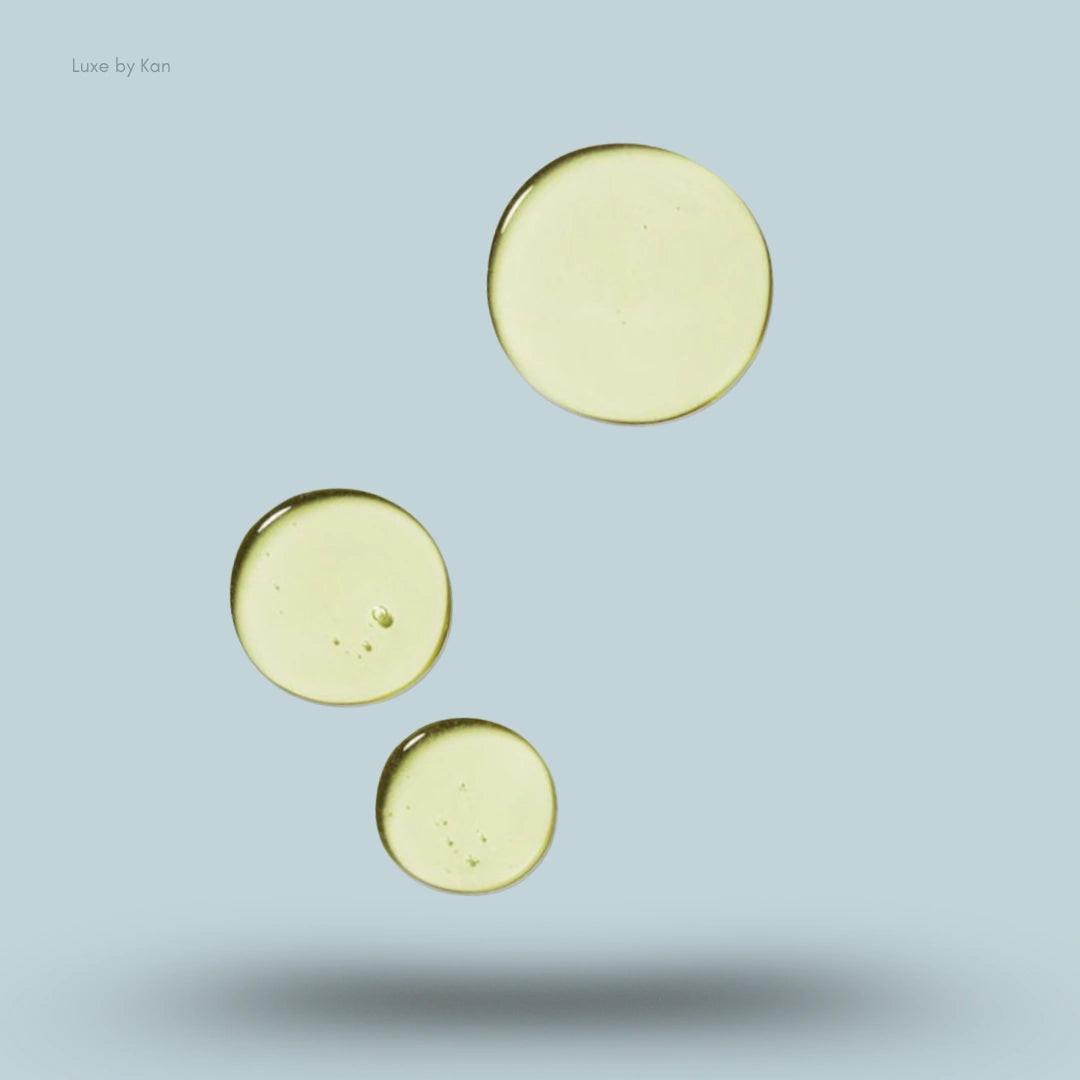 Three golden yellow drops are levitating on a light blue background, representing the Rahua voluminous shampoo.