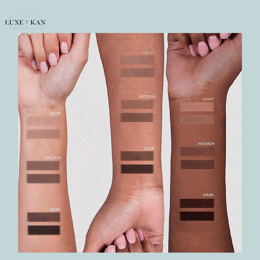 Three arms of varying skin tones, ranging from light to dark, each displaying swatches of brow pomade in light, medium, and dark shades.
