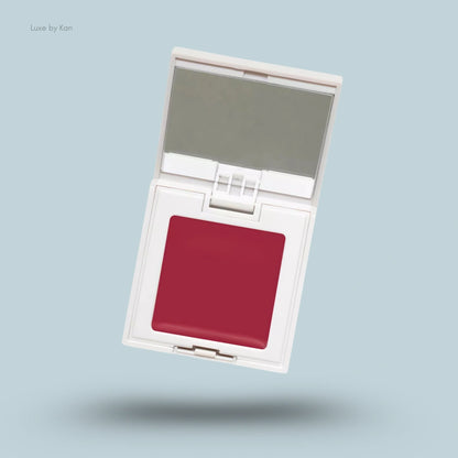 Refy cream blush in a white compact case, open to reveal a crimson cream blush and a mirror.