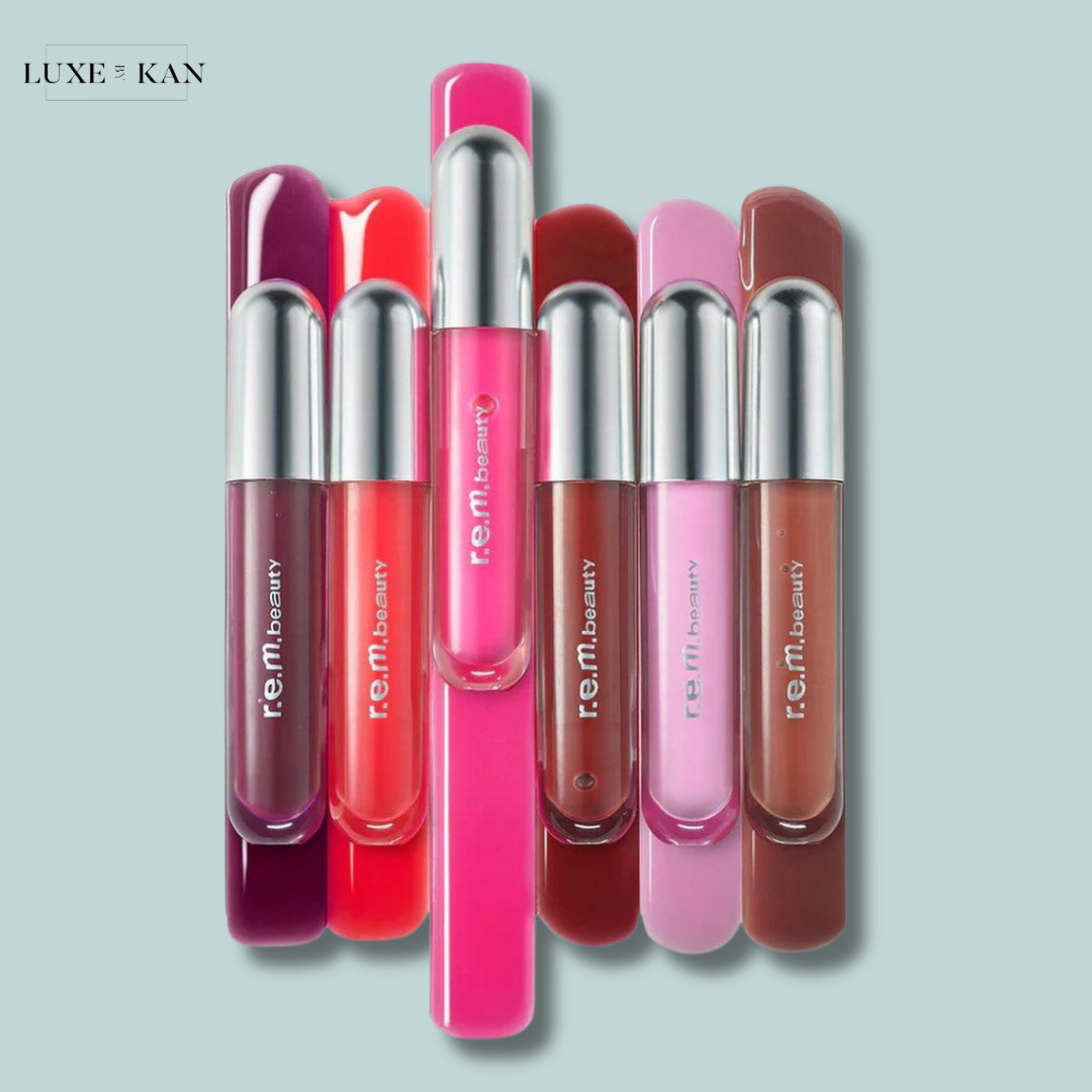 A collection of colorful r.e.m. beauty lip products arranged in a row, featuring shades of pink, red, and brown.
