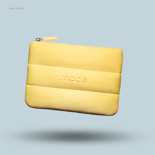 Close-up of a yellow padded Rhode Bubble Bag appearing to levitate, with the brand name "rhode" embossed on the surface.