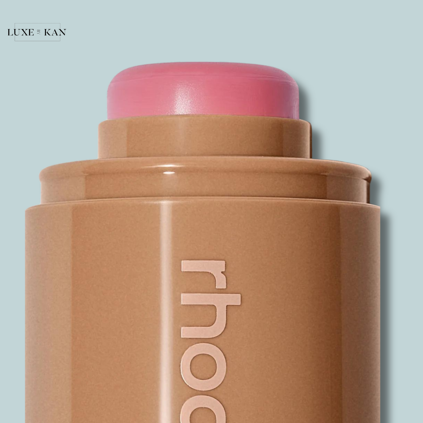 Close-up of a bronzer stick with a pink top, featuring the brand name "rhod" in elegant lettering on the side.
