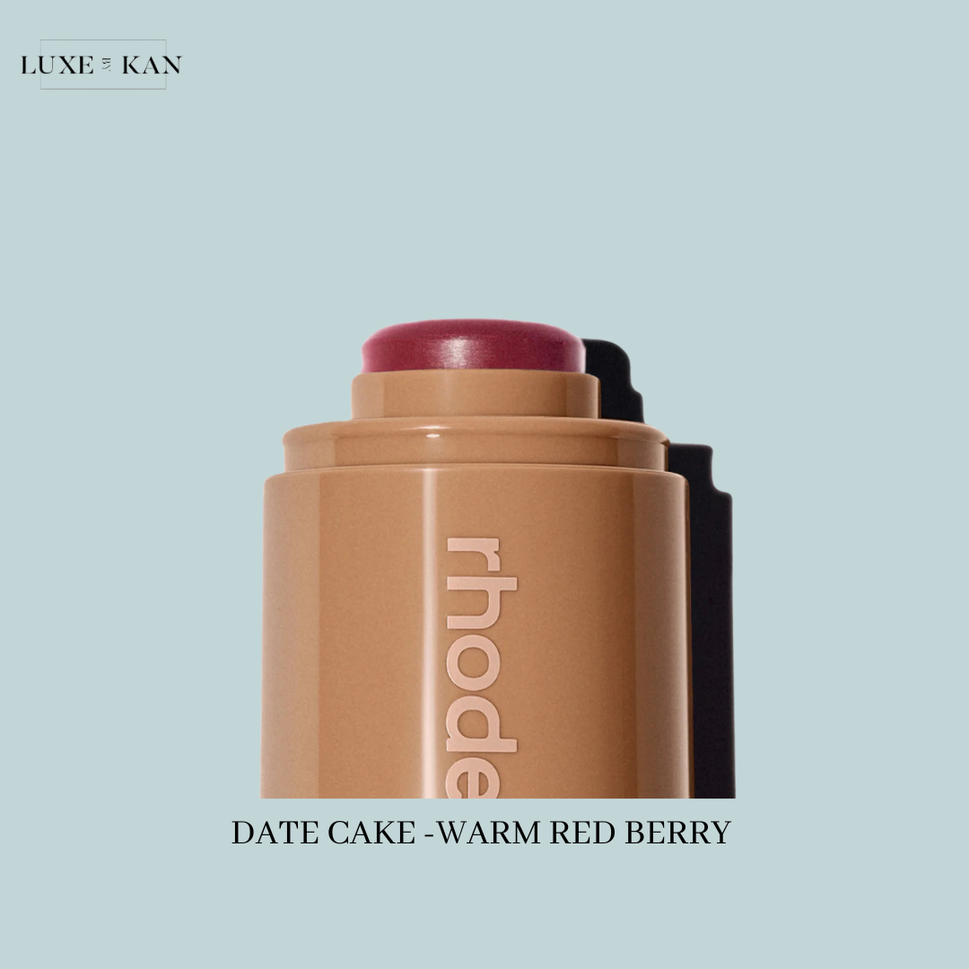 A close-up of a Rhodes cosmetic stick labeled "Date Cake - Warm Red Berry," showcasing a deep berry tip.