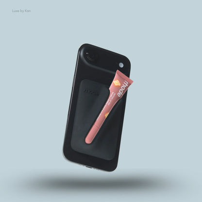 A black Rhode Snap-On Lip Balm Holder With MagSafe Case with a pink Peptide Lip Treatment tube secured to the back.