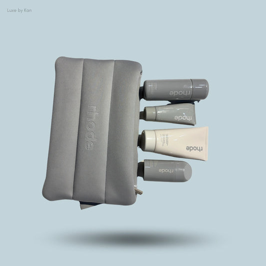Rhode skincare kit shows grey pouch with embossed logo and four tubes/bottles of Peptide Lip Treatment, Barrier Restore Cream, etc.
