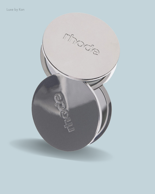 Two silver compact mirrors with the embossed "rhode" logo.