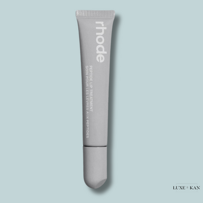 A sleek, grey tube of rhode Peptide Lip Treatment against a light blue background, emphasizing its skincare purpose.