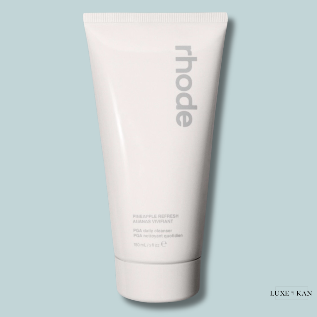 A sleek white tube of rhode Pineapple Refresh daily cleanser on a pastel blue background.
