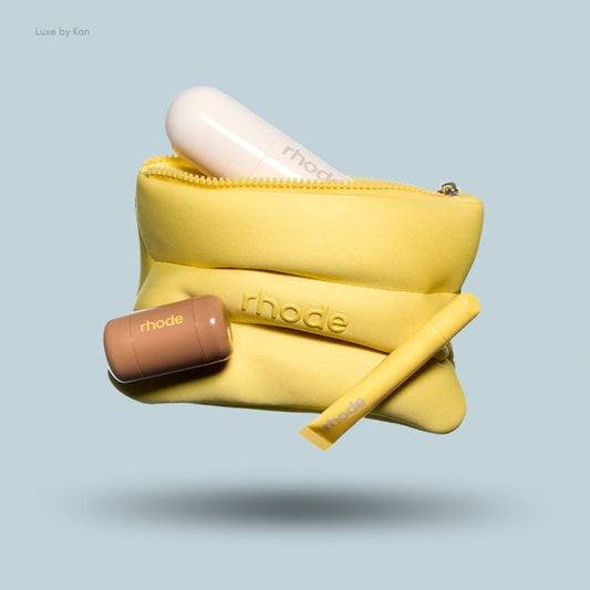 Rhode Summer Kit featuring a yellow pouch with an embossed logo, a white serum bottle, a brown Peptide Lip Treatment, and a yellow Lip Treatment.
