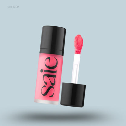 An open tube of SAIE Dew Blush in a bright pink shade with a doe foot applicator.