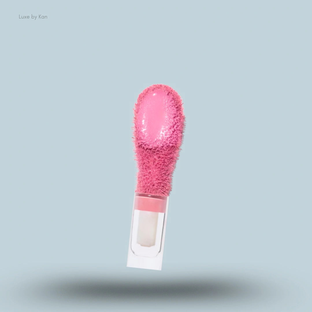 A fluffy, bright pink doe foot applicator of Saie Dew Blush with product coated on the tip.