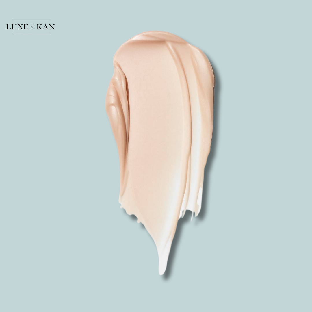 A creamy, light beige cosmetics swatch on a soothing blue background, showcasing a smooth, glossy texture.