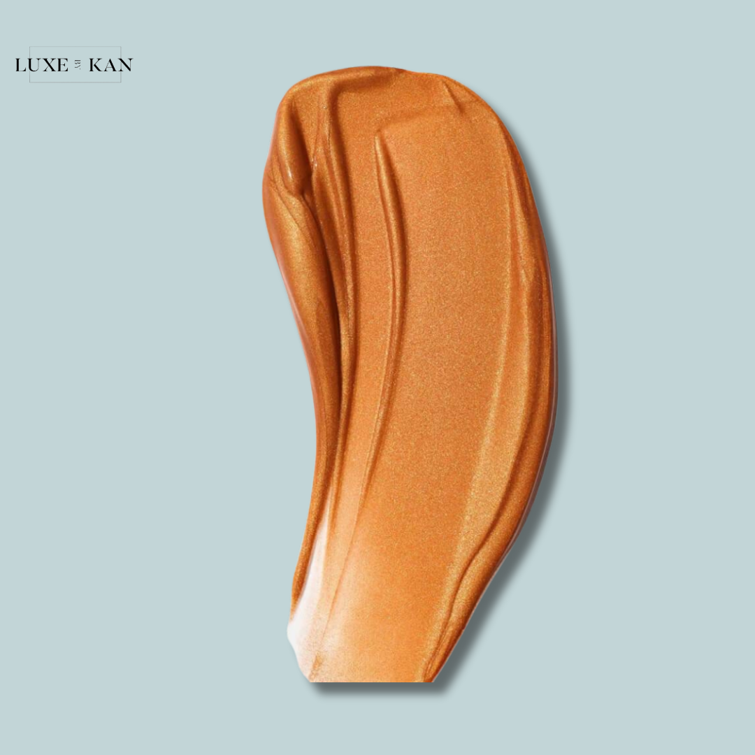 Swatch of Saie Glowy Super Gel in Sunglow, a radiant bronze gel highlighter with a dewy, light-reflecting finish on a blue background.