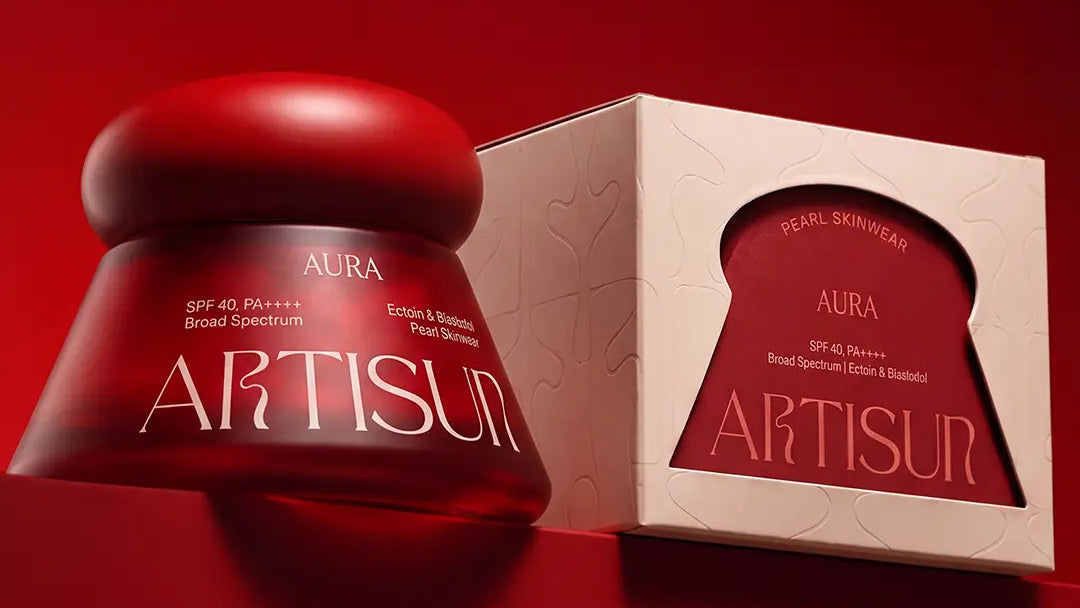 Artisun Aura Pearl sunscreen SPF 40 PA++++ with its glass jar and packaging on a maroon background
