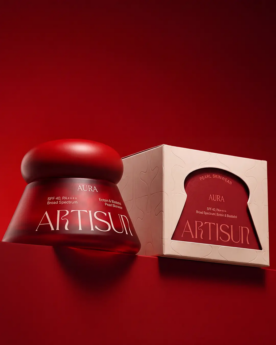 Artisun Aura Pearl sunscreen SPF 40 PA++++ with its glass jar and packaging on a maroon background