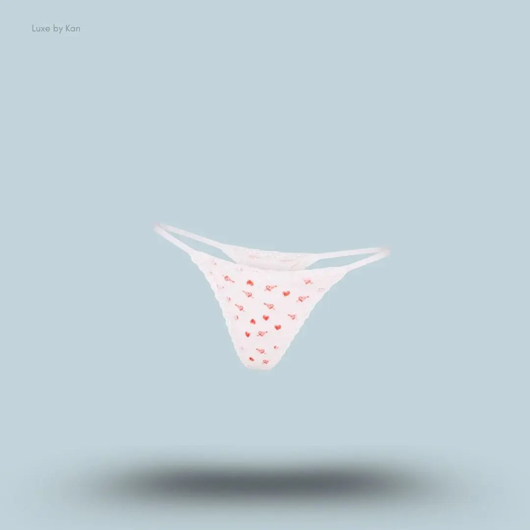 SKIMS Lightweight Cotton Pointelle Lace String Thong in Snow Arrowed Hearts, flat lay on light blue background