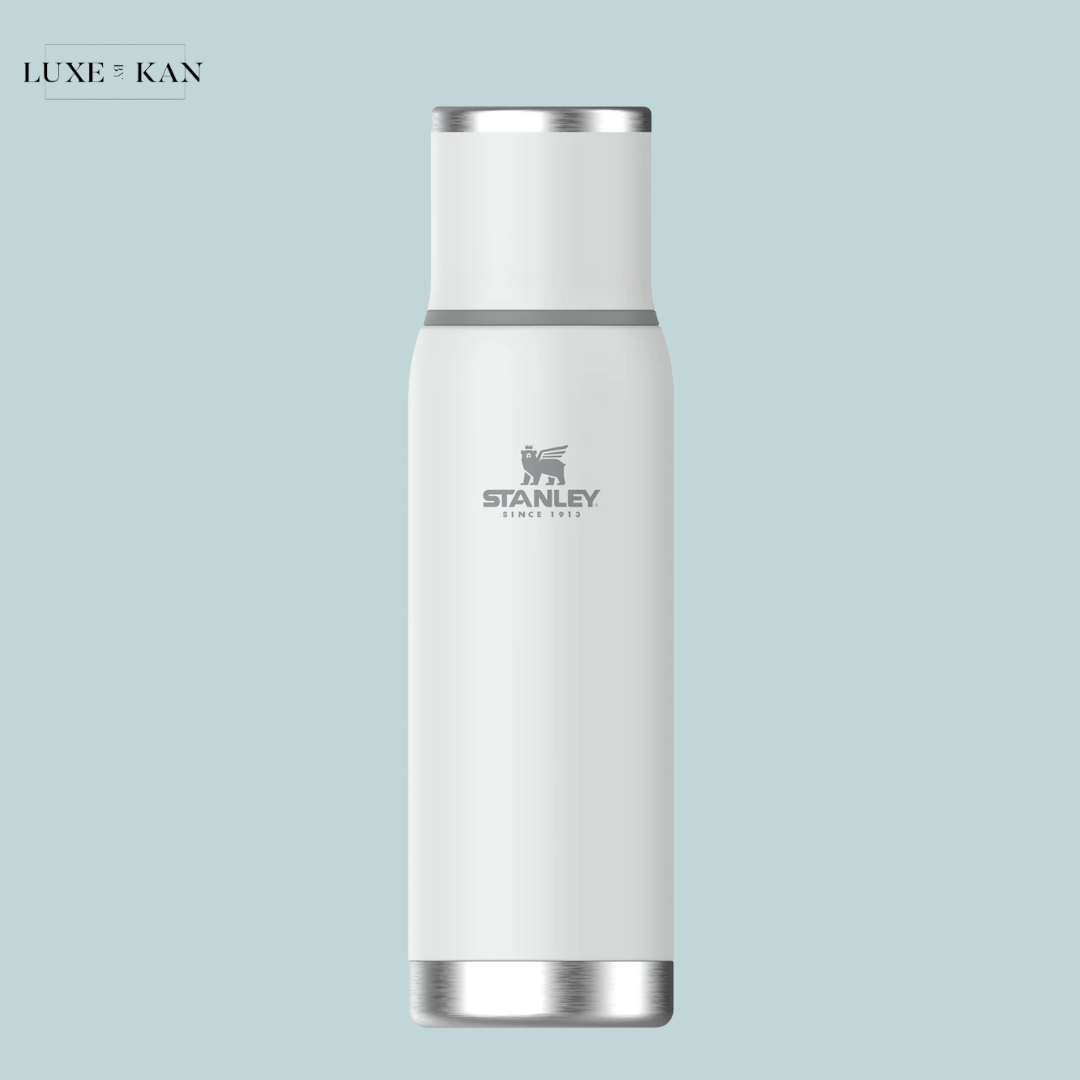 A sleek, white stainless steel 'Adventure To-Go' water bottle by Stanley, featuring a silver logo and modern design.