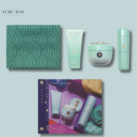 Flat lay of Tatcha skincare products including a cleanser, moisturizer, and tonic, displayed with a green patterned cloth and colorful box.