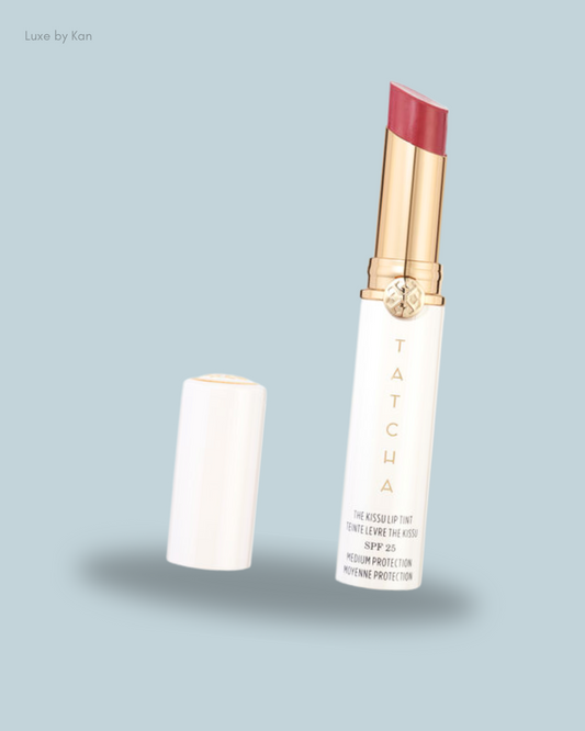 A tube of Tatcha's Kissu Lip Tint in rosy pink, with SPF 25, positioned beside its cap.