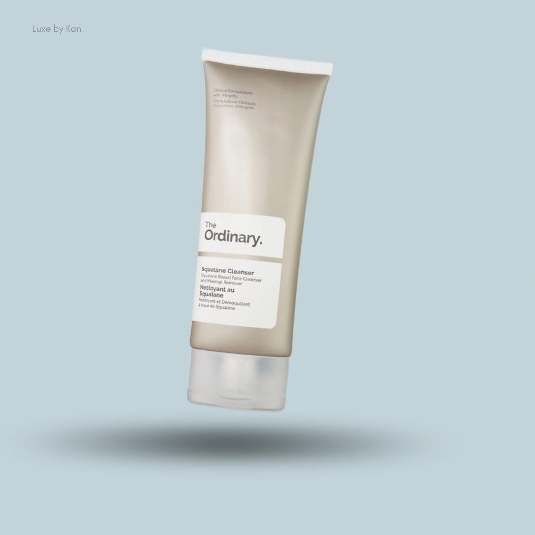 A beige tube of The Ordinary Squalane Cleanser stands at an angle against a light blue background with a soft shadow.