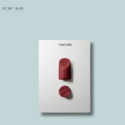 A Tom Ford lipstick tube and swatch on a minimalist white background, showcasing a rich burgundy shade with embossed initials.