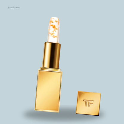A luxurious gold Tom Ford Soleil Lip Blush with a clear top featuring gold flakes, housed in a golden case embossed with "TF."