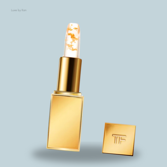 A luxurious gold Tom Ford Soleil Lip Blush with a clear top featuring gold flakes, housed in a golden case embossed with "TF."