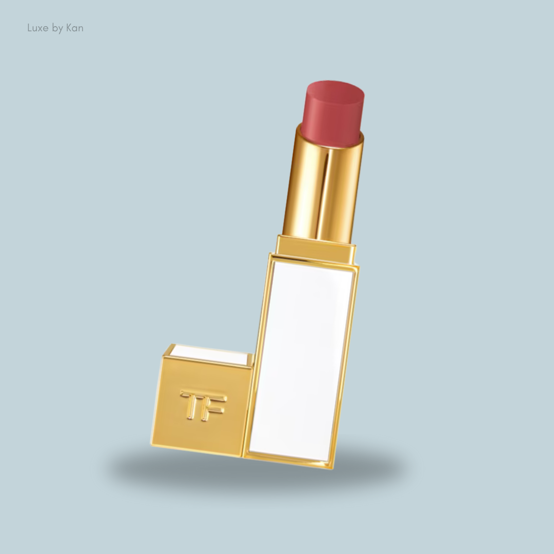 A luxurious gold lipstick with a soft pink shade, featuring a sleek design and a white label, set against a light blue background. 