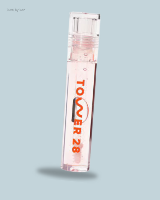 A clear tube of Tower 28 ShineOn Lip Jelly in a light pink shade, featuring an orange logo.