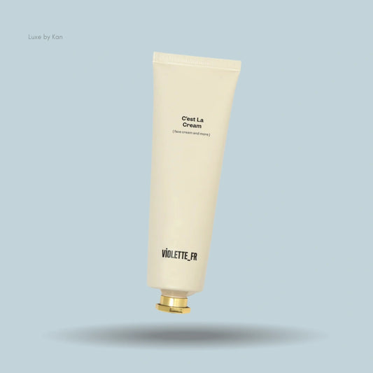 Tube of Violette FR C'est La Cream (face cream and more) with a gold cap against a blue background.
