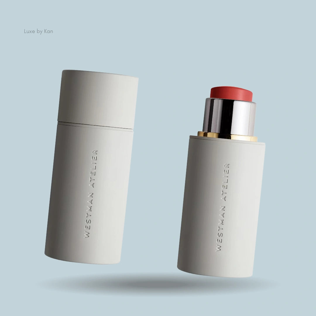 Two Westman Atelier Baby Cheeks Blush Sticks in matte off-white packaging, one capped and one open showing a coral shade.