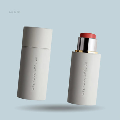 Two Westman Atelier Baby Cheeks Blush Sticks in matte off-white packaging, one capped and one open showing a coral shade.