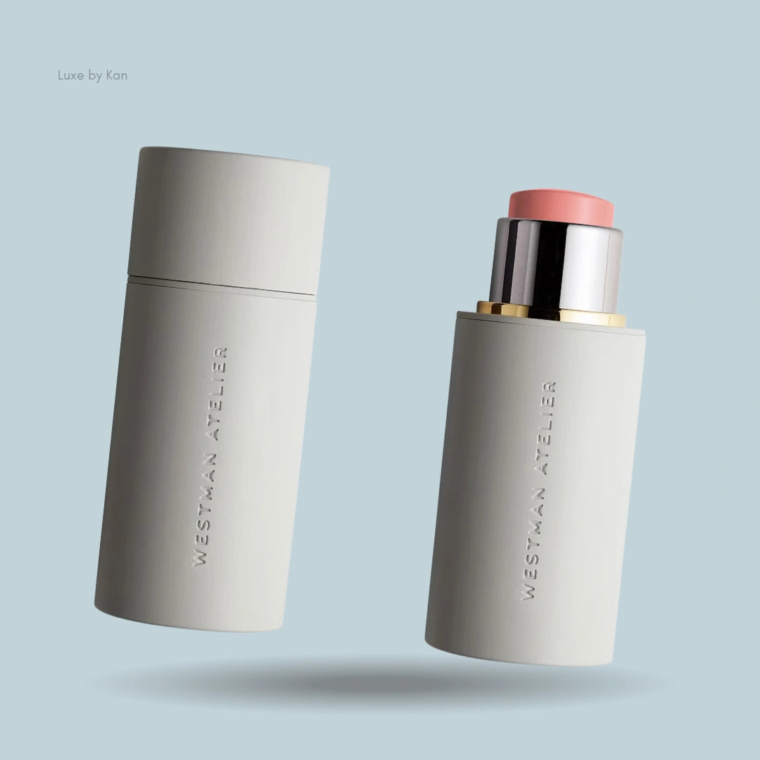 Two Westman Atelier Baby Cheeks Blush Sticks, one closed and one open revealing the peachy-pink cream blush.