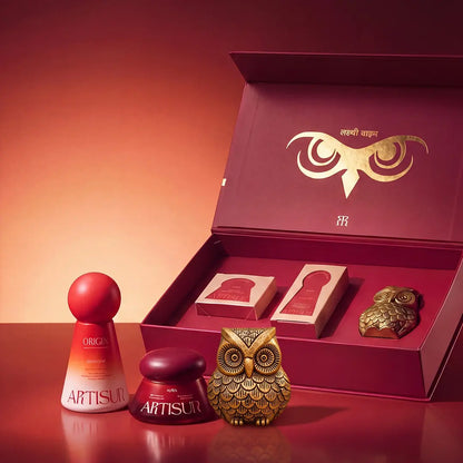 Artisun Vahana Vol 1 Diwali gift box open with Origin and Aura sunscreens and a brass owl on a red background