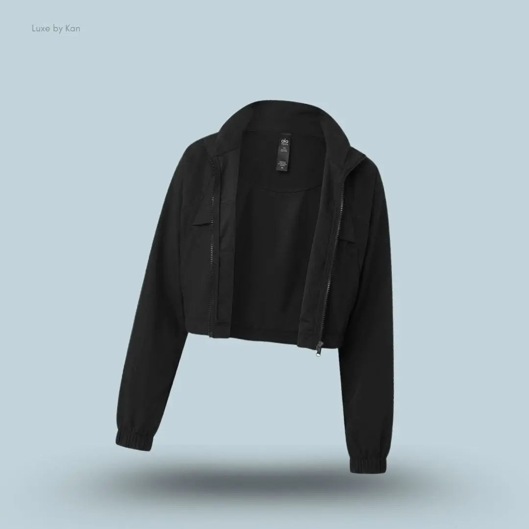 Alo Cropped Playmaker Jacket in Black, flat lay on light blue background