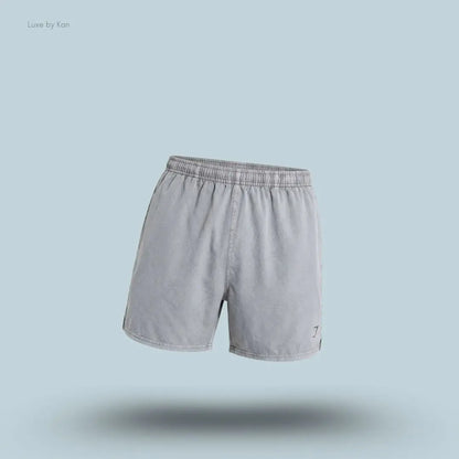 Gymshark Washed Pastels Shorts in black displayed on a blue background with a relaxed athletic shorts design