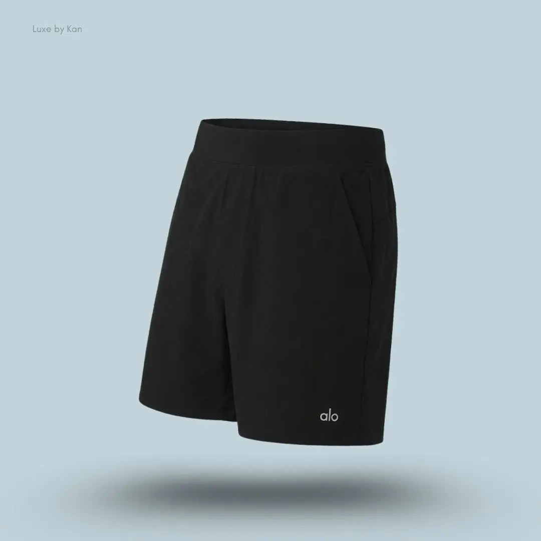 Alo 5 inch Repetition Short in Black, flat lay on light blue background